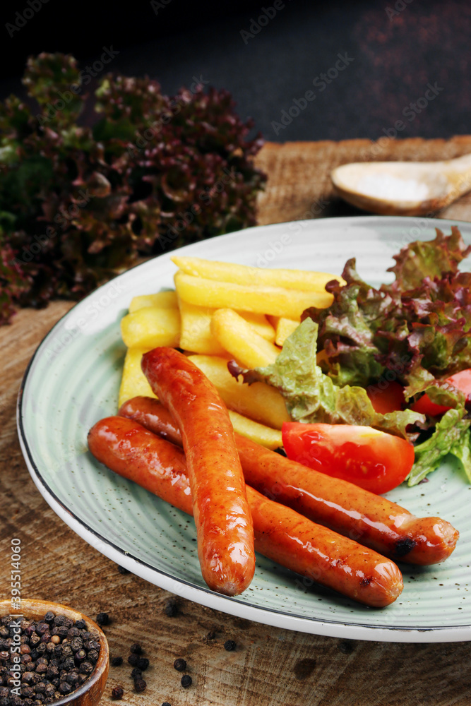 sausages with french fries and salad on wooden table closeup. sausages with french fries and salad on wooden table closeup.