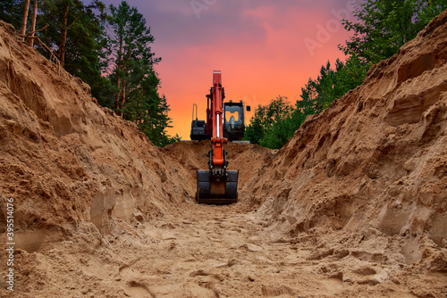 Leinwand Poster Excavator dig trench at forest area on amazing sunset background
