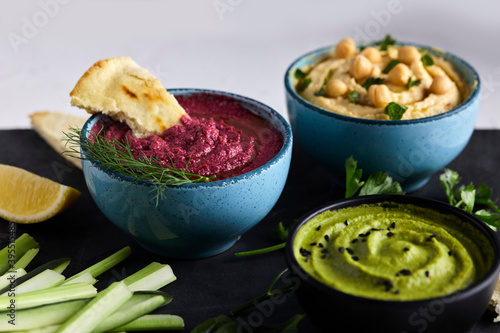 Various types of hummus served with fresh vegetables and pita bread photo