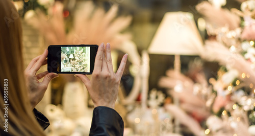 Woman taking picture of beautiful Christmas store window display with her smartphone.