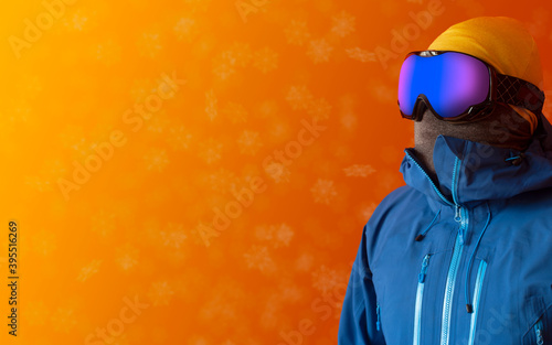 Man in outdoor clothes ready for some winter action. Snow falling gently in the background with copy space for additional content. 