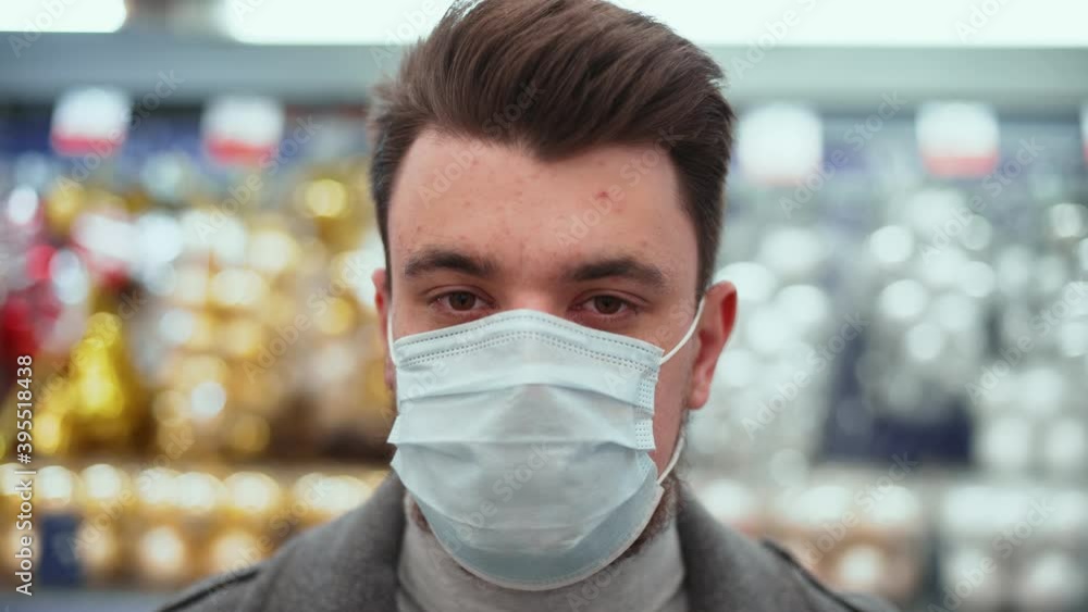 Close-up shot of a handsome caucasian businessman in grey coat and medical mask shopping in supermarket for christmas during coronavirus. Close-up shot of a handsome caucasian businessman in grey coat and medical mask shopping in supermarket for christmas during coronavirus.