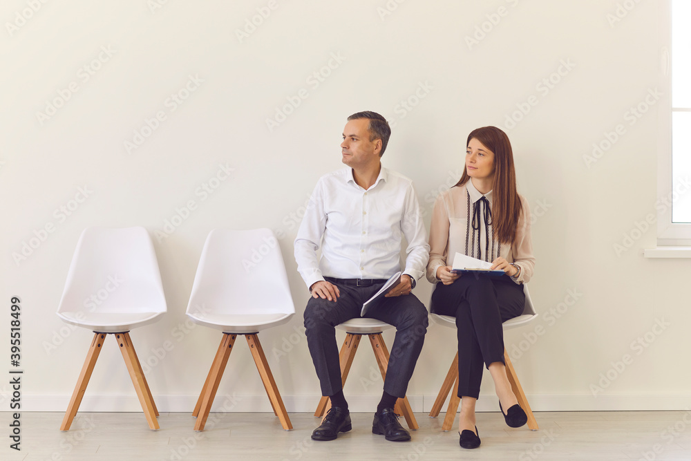 Obraz premium Confident young job candidates sitting on chairs in the hall waiting for their interview