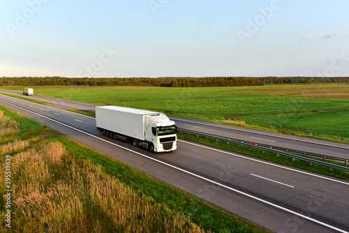 Truck with semi-trailer driving along highway on the blye sky background. Goods delivery by roads. Services and Transport logistics. Soft focus. photo