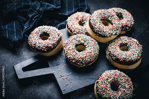 Oven-baked vegan donuts with dark chocolate icing and colourful sprinkles photo