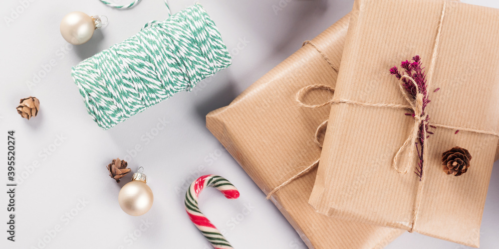Xmas wrapped gifts stack and green twine on gray background with Christmas ornament Xmas wrapped gifts stack and green twine on gray background with Christmas ornament