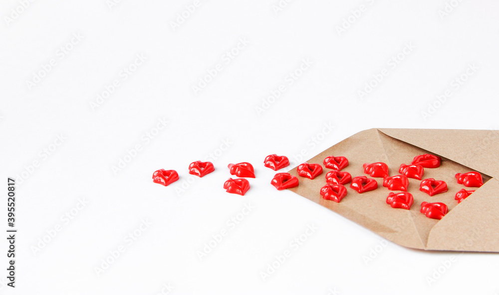 An envelope made of Kraft paper on a light background from which red kisses spilled out. An envelope made of Kraft paper on a light background from which red kisses spilled out.