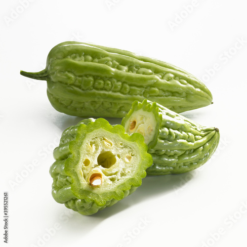 A whole and a halved bitter cucumber on a white background photo