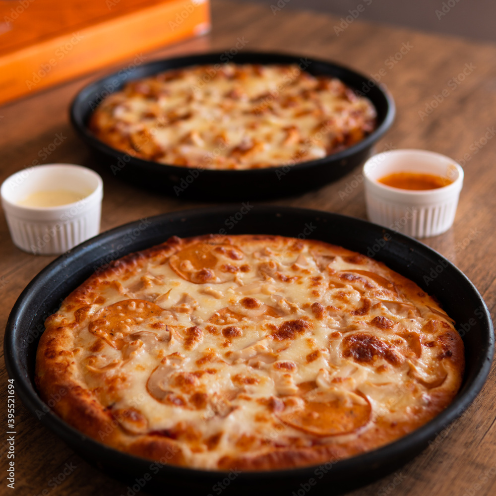 Chicken Tikka Pizza with Extra cheese on top and onion on a wooden table with chili and garlic sauce