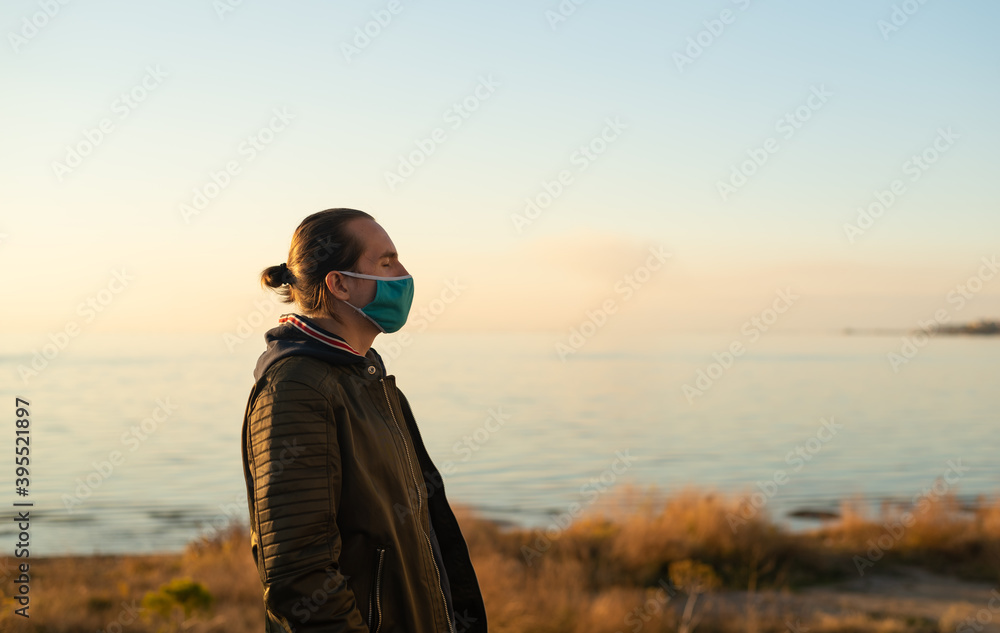 Fototapeta premium Man with hair bun and reusable face mask outdoors.