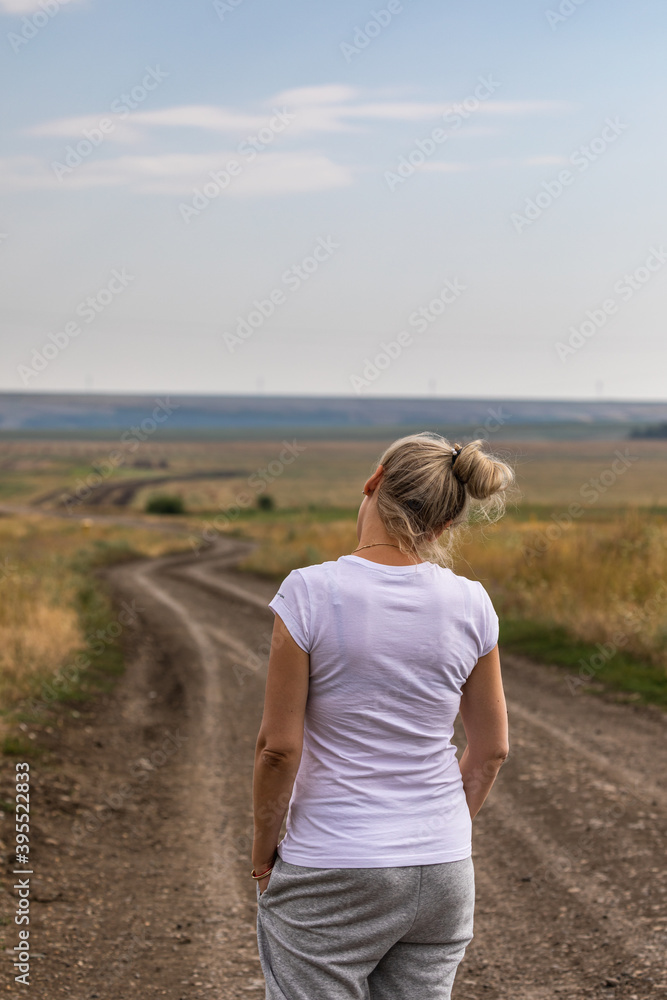 The girl is walking along a country road.