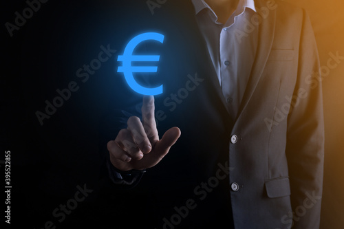 Businessman holds money coin icons (EUR or Euro) on dark tone background..Growing money concept for business investment and finance