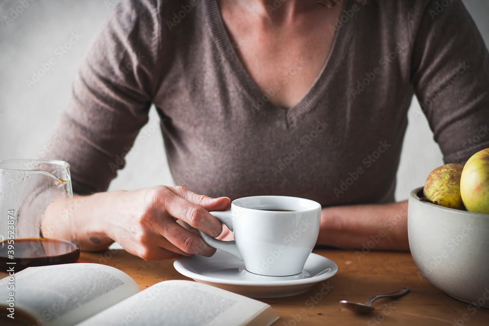Woman's hand with a coffee cup and a book Woman's hand with a coffee cup and a book