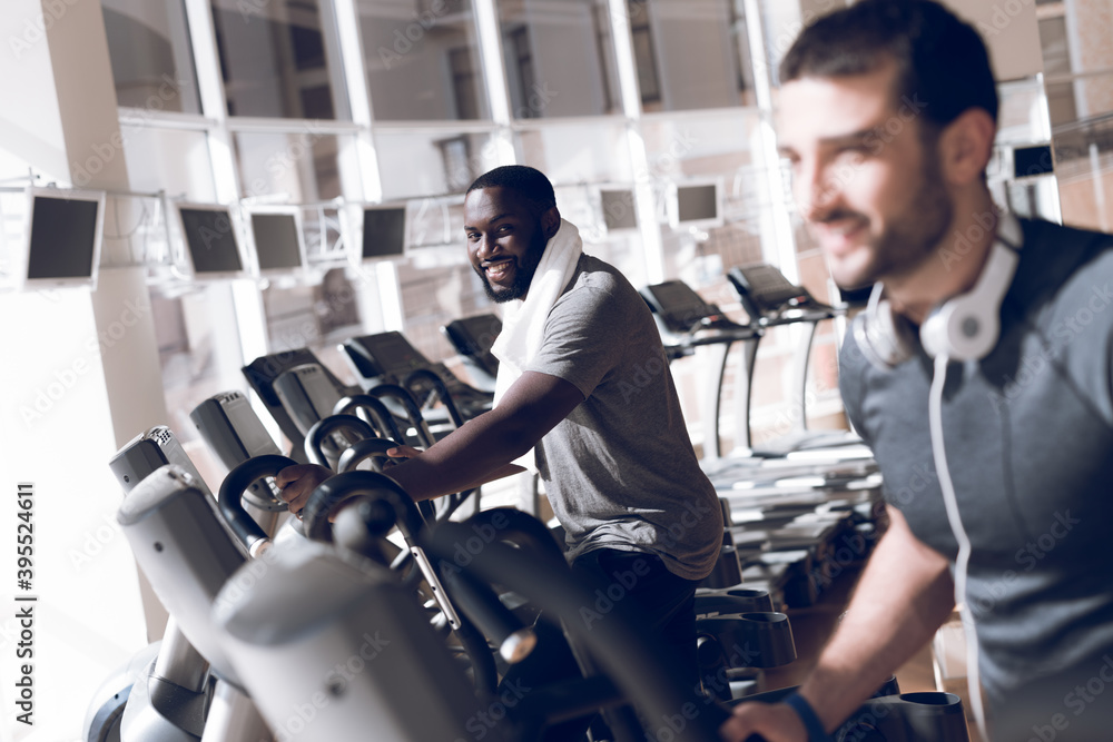 Two men are engaged on treadmills in modern gym. Two men are engaged on treadmills in modern gym.