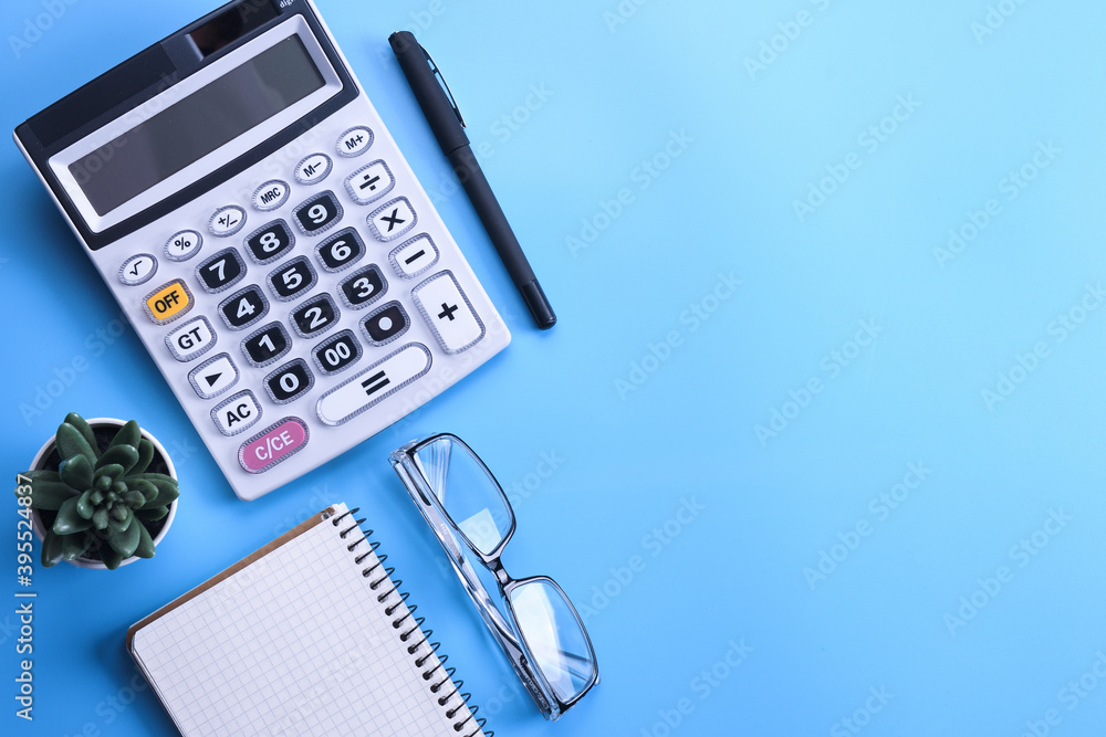 Calculator keypad on a blue background.Notebook, pen, glasses, desktop. Finances Top view. Copy space Calculator keypad on a blue background.Notebook, pen, glasses, desktop. Finances Top view. Copy space