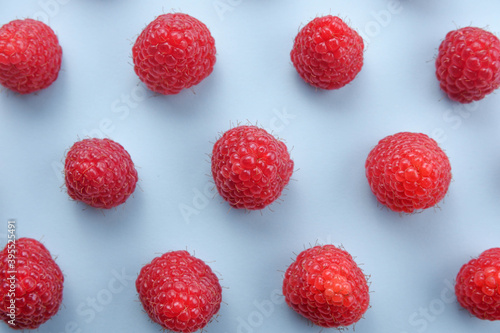 Pattern of raspberry on blue background. Flat lay summer berries - red raspberries. Creative minimalism