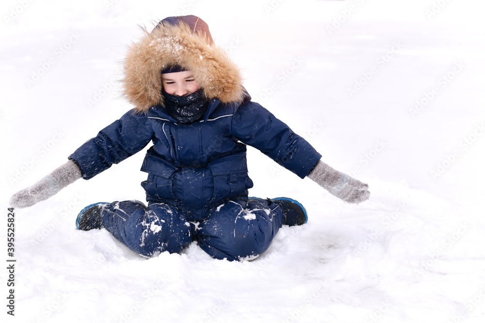 The child is warmly dressed. Sits with open arms in mittens and looks with surprise and joy at the large of snow. The child is warmly dressed. Sits with open arms in mittens and looks with surprise and joy at the large of snow.