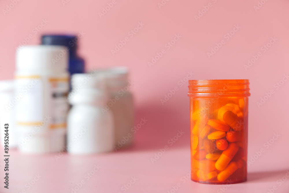 close up of pills and capsule container on pink background close up of pills and capsule container on pink background