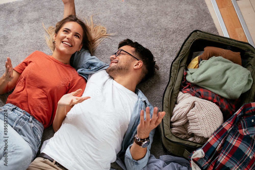 Obraz premium Loving couple packing clothes into travel bag. Boyfriend and girlfriend preparing for the trip.