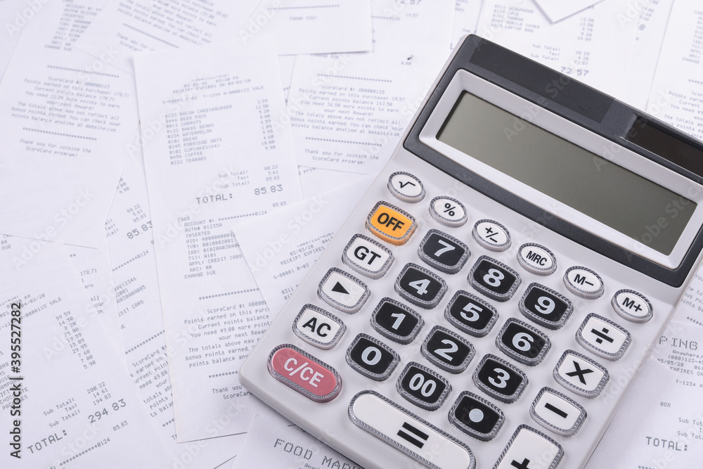 Calculator for counting on a pile of checks from purchases from the store on a wooden background. Top view. Place for text.Copy space Calculator for counting on a pile of checks from purchases from the store on a wooden background. Top view. Place for text.Copy space