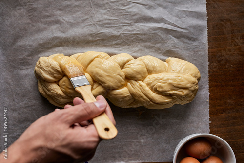 A braided loaf being spread with egg yolk photo