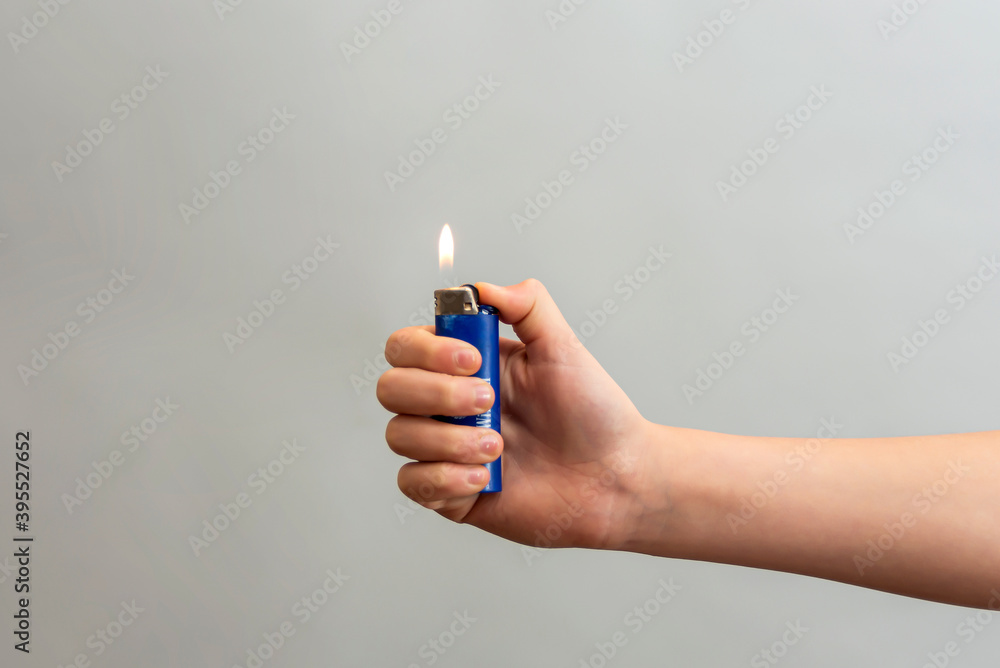 The girl wrapped her hand around the lighter and lit her finger on a gray  background. Stock-foto | Adobe Stock