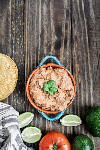 Refried beans with fried corn tortillas, avocados, tomatoes and fresh limes photo