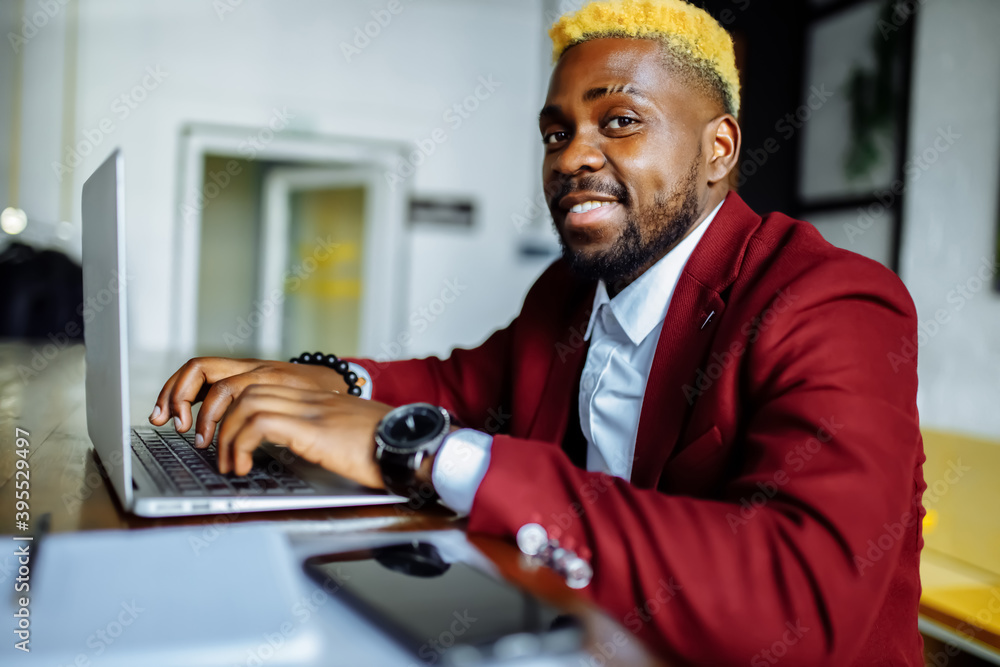 Smiling businessman in a marsala jacket working on laptop computer in office Smiling businessman in a marsala jacket working on laptop computer in office