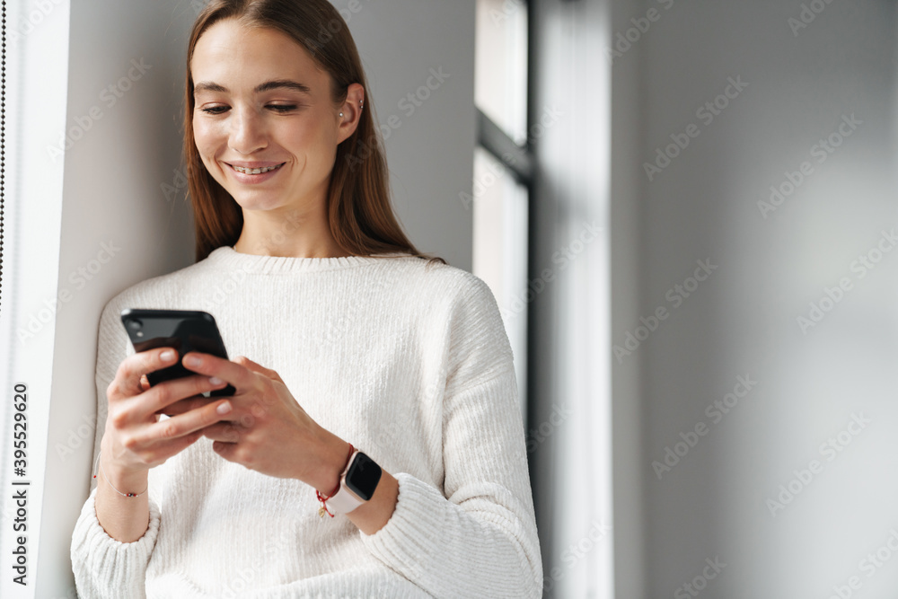 Joyful beautiful woman using mobile phone while leaning on wall Joyful beautiful woman using mobile phone while leaning on wall