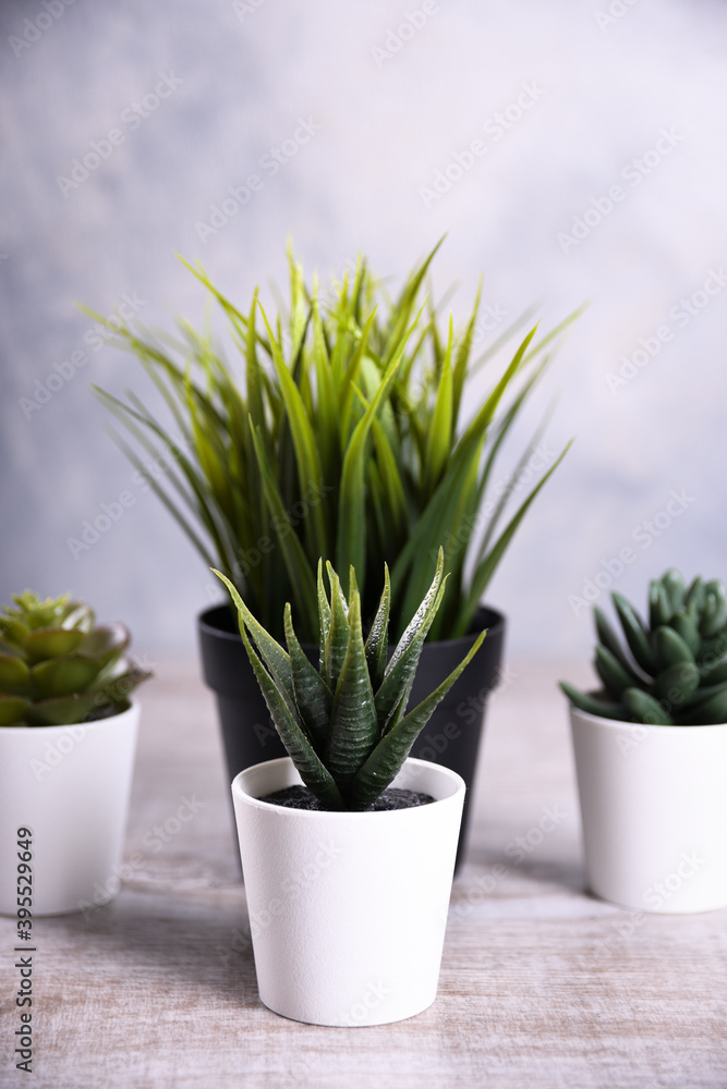 Artificial flowers grass different form in a pot on wooden background close up with copy space and text Artificial flowers grass different form in a pot on wooden background close up with copy space and text
