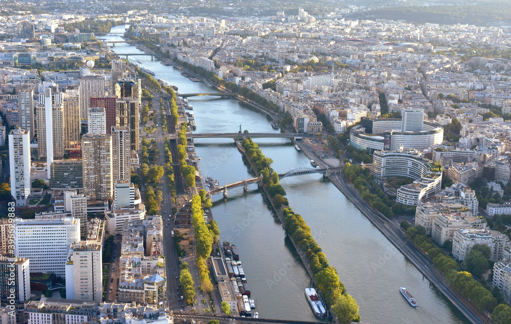 Parisian cityscape at sunset, view from Eiffel Tower with bridges over the Seine River and Ile aux Cygnes. Paris, France.