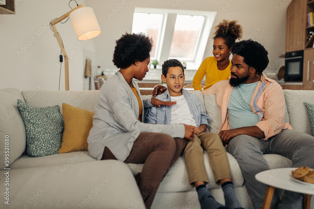 Afro parents and their children bonding at home. Sitting on sofa in the living room and socializing Afro parents and their children bonding at home. Sitting on sofa in the living room and socializing