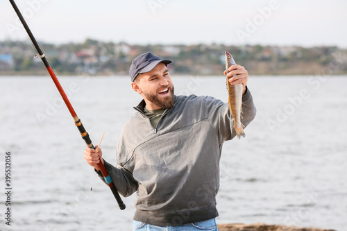 Happy young man fishing on river
