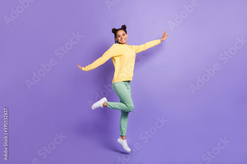 Full size profile photo of optimistic girl jump wear yellow shirt trousers sneakers isolated on lilac color background © deagreez