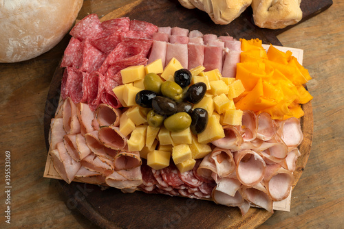 table of cold cuts and various cheeses with olives, homemade bread chopped with loin, ham, bondiola, bacon, salami, and a variety of cheeses photo