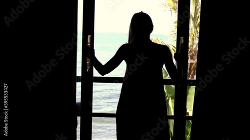 Woman opening door and walking out on terrace with beautiful sea view, 240fps 
 photo