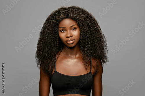 Beauty fashion portrait of young beautiful african american woman with volume,curly hair against gray background