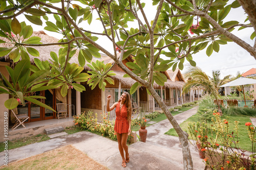 Attractive young woman in red dress walk near plumeria flower  in tropical garden photo