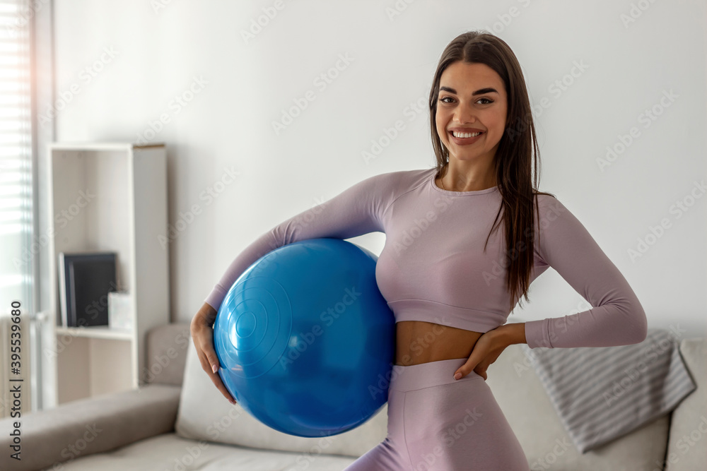Young sportswoman holding fitness ball.Photo of young fit Caucasian girl holding exercise ball and smiling at camera.Pretty young girl with fit ball at home.Fitness,sport and healthy lifestyle concept Young sportswoman holding fitness ball.Photo of young fit Caucasian girl holding exercise ball and smiling at camera.Pretty young girl with fit ball at home.Fitness,sport and healthy lifestyle concept