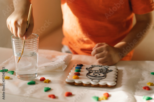 A child paints glazed gingerbread cookies with food coloring. Creativity and hobbies