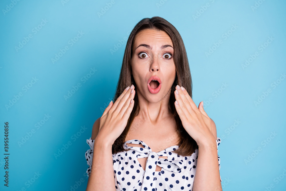 Photo of surprised young lady open mouth hands face staring camera wear dotted blouse isolated blue color background Photo of surprised young lady open mouth hands face staring camera wear dotted blouse isolated blue color background