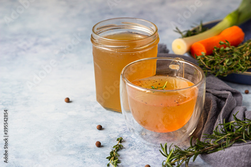 Φωτογραφία Homemade bone broth in glass mug and vegetables, blue concrete background