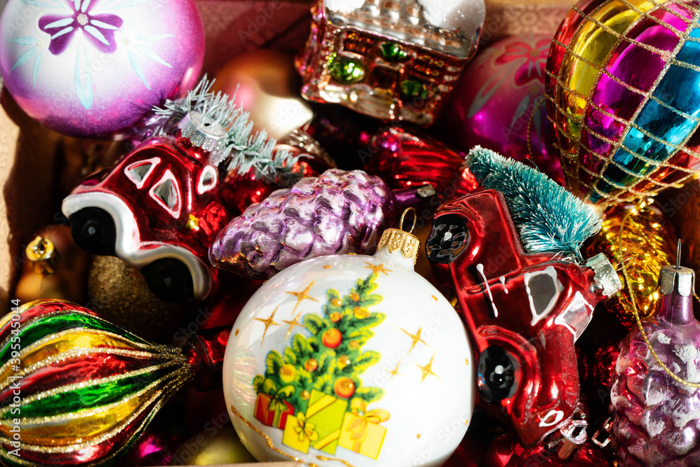 Various Christmas glass decorations (ball, house, car, pine cone, balloon) are in the box. Multicolored directions for the Christmas tree close-up. New year and Christmas concept