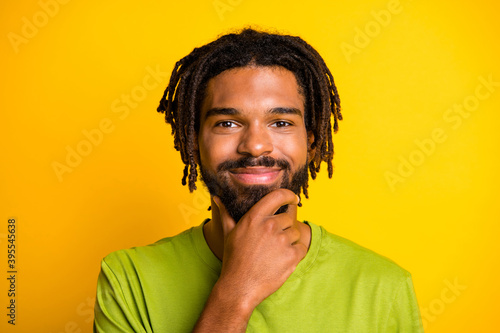 Portrait of positive minded dark skin guy think concept touch chin hands isolated over bright yellow color background