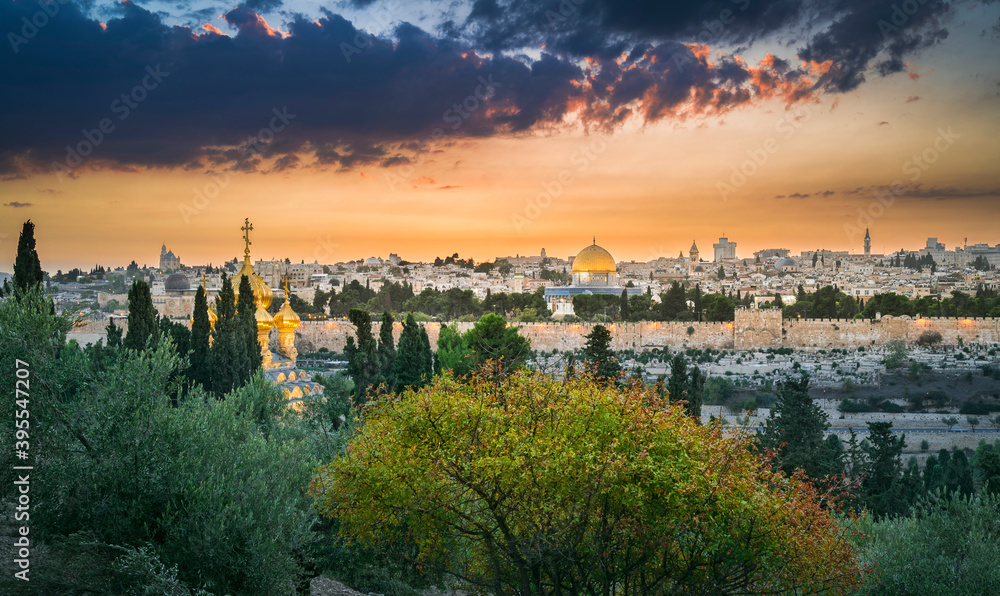 Beautiful dramatic autumn sunset over the Old City Jerusalem, with the Dome of the Rock, the Golden Gate and the Russian Orthodox church of Mary Magdalene seen through fall trees on Mount of Olives