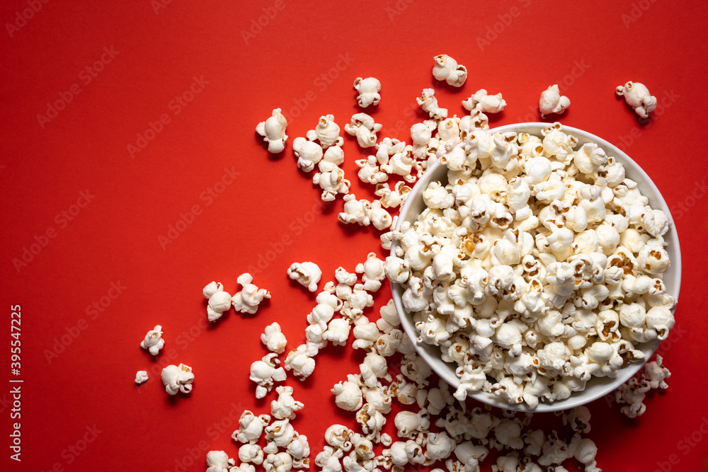 bowl of popcorn on a red background with others scattered outside. view from above bowl of popcorn on a red background with others scattered outside. view from above