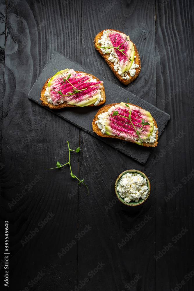 Healthy breakfast toasts from sliced watermelon radish or chinese daikon with goat cheese, microgreen and chia seeds, vertical image Healthy breakfast toasts from sliced watermelon radish or chinese daikon with goat cheese, microgreen and chia seeds, vertical image