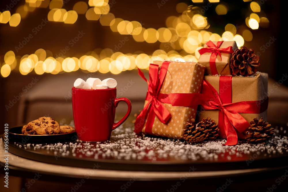 Christmas drink. Red cup of hot chocolate with marshmallows, cookies and gifts on festive background Christmas drink. Red cup of hot chocolate with marshmallows, cookies and gifts on festive background