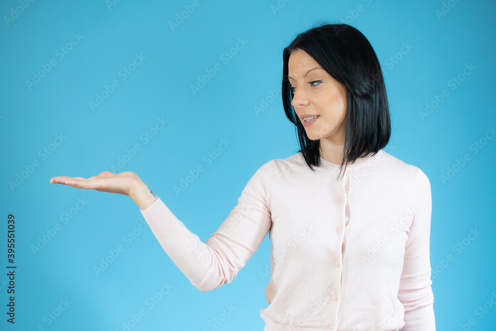 Young brunette woman with blue eyes wearing casual sweater pointing aside with hands open palms showing copy space, presenting advertisement smiling Young brunette woman with blue eyes wearing casual sweater pointing aside with hands open palms showing copy space, presenting advertisement smiling