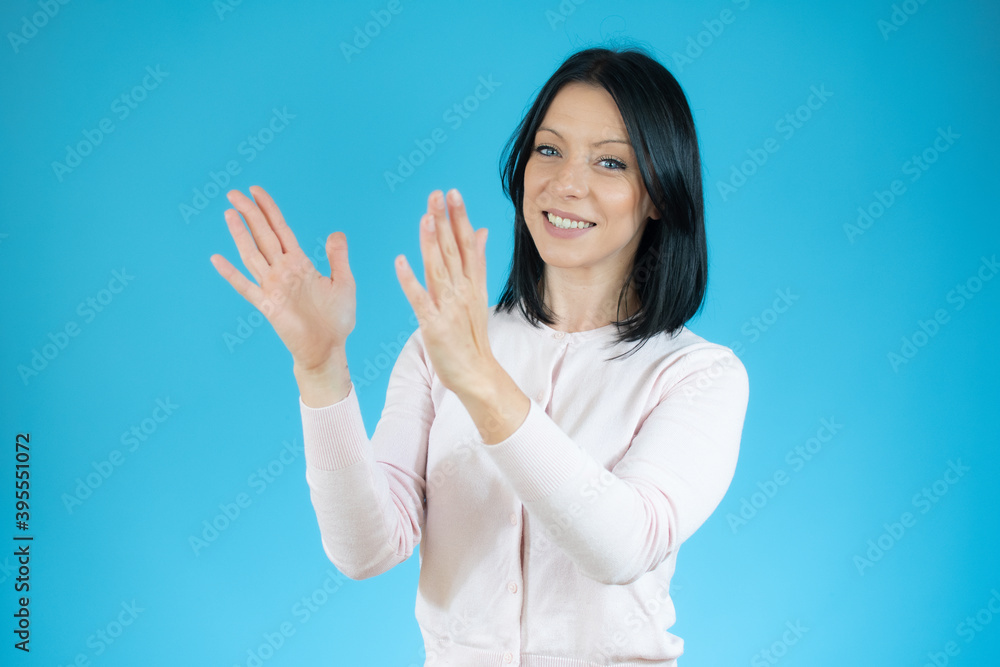 Young brunette woman with blue eyes wearing casual sweater over isolated blue background clapping and applauding happy and joyful, smiling proud hands together Young brunette woman with blue eyes wearing casual sweater over isolated blue background clapping and applauding happy and joyful, smiling proud hands together